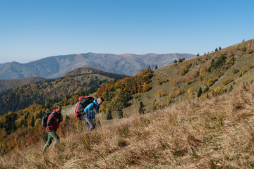 Obraz premium Paragliders, trekkers, mountaineers, walking up hill to a paragliding starting point, on a sunny morning in mountains.