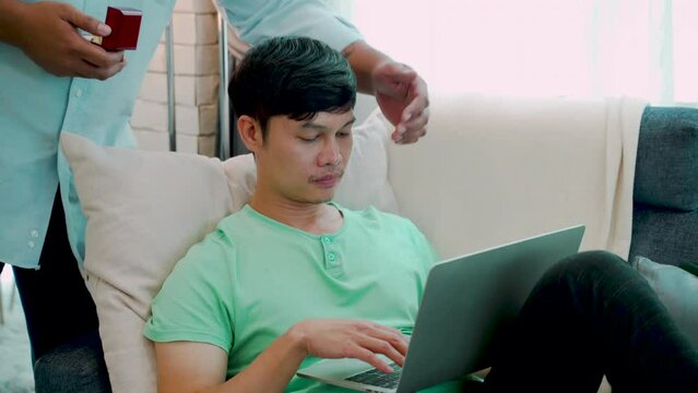4K The man lies down and works on his favorite sofa. A couple walked in, closed their eyes, and made a surprise offer. Give a ring to ask for marriage. the love and friendship of LGBTQ couples.