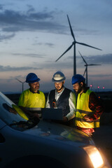 Team of technician and engineer working in wind turbine farm at night, planing renewable energy...