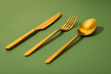 Golden cutlery set on the green background. 