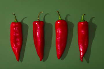 Four sweet red peppers on the green background.