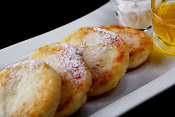 Fried cottage cheese pancakes with honey and sour cream
