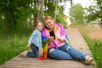 A mother with an LGBT flag and her little daughter take selfies on their smartphone. Funny girl and her mom.