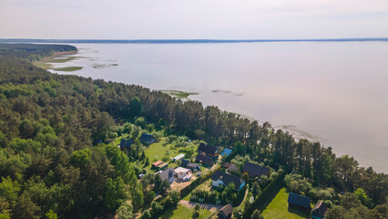 Obraz premium Aerial view of lake and small village. Village near the lake. Aerial view of the village and trees on the shore of lake.