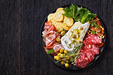 savory baked brie with crackers, salami, nuts, ham