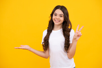 Impressed teenage girl showing recommendation copyspace. Child teenager points away, pointing aside at copy space. Happy teenager, positive and smiling emotions of teen girl.