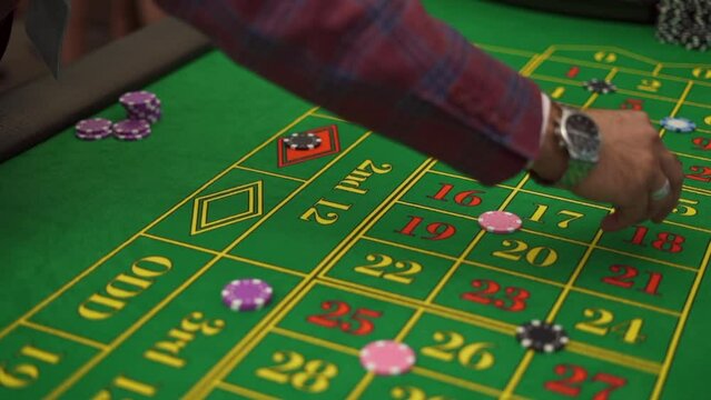Top view hands of men and women betting with chips on a gaming roulette table in a casino. the lucky gentleman rates in casino. Slow motion shot. High quality FullHD footage