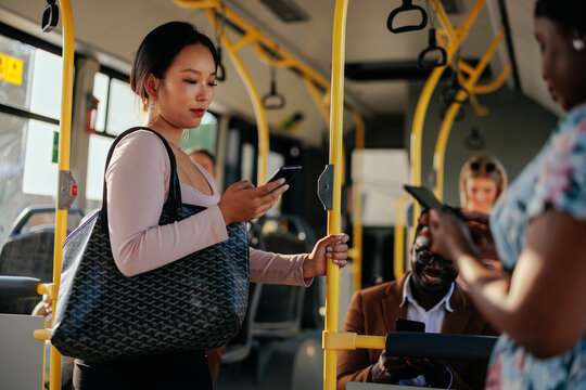 Young Asian woman texting in public transportation