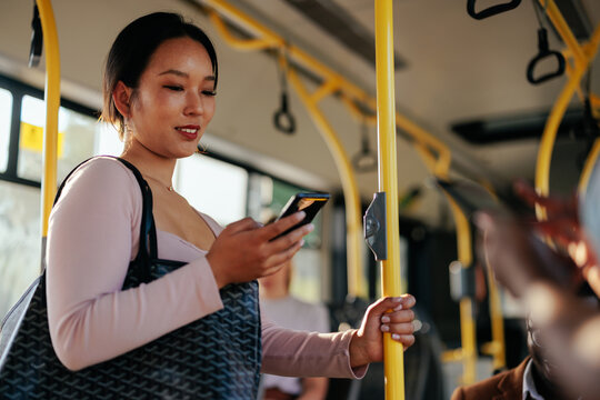 Asian woman checking social media on phone in bus