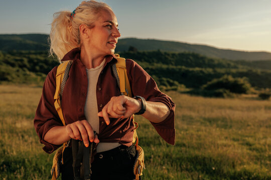Middle aged woman hiking in mountain checking smartwatch maps