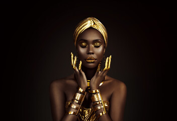 Portrait closeup Beauty fantasy african woman face in gold paint. Golden shiny black skin. Fashion model girl goddess hand fingers posing. Arab turban jewellery bracelets. Professional metallic makeup - Powered by Adobe