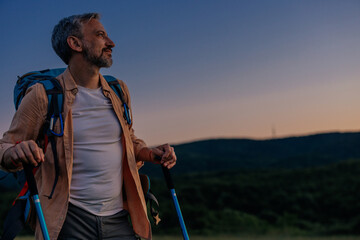 Middle aged man with hiking gear in sunset