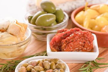 Selection of vegetable antipasti  - sun-dried tomatoes, pickled artichokes, capers, baby peppers and olives with rosemary. Menu background. Vegetable appetizer