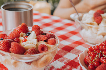 Healthy organic raw child diet eco friendly food.Bright colorful Red checked tablecloth.raspberry, strawberry, black currant, coffee cup. family having fresh summer morning breakfast picnic 