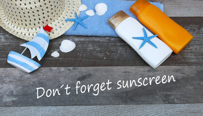 Towel, sunscreen and hat with the text Don't forget sunscreen.