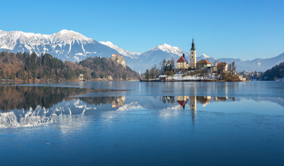 Fototapeta na wymiar Lake Bled on a cold winter day with frozen ice. Icy water on the lake. 