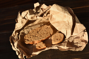 Piece of dried bread on crumpled paper on dark background. Need food. War, hunger and poverty.