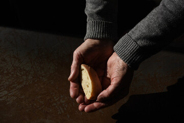 A piece of bread in the palms of an elderly poor woman. . Concept of war, poverty, crisis and...