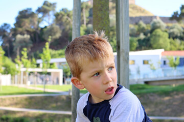 The blond boy turns his head to the side and looks off into the distance with interest. A curious...
