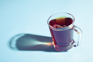 A glass of hot black tea on blue background.