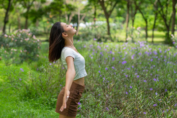 Obraz premium Portrait photo of a young beautiful asian female lady in white top embracing the breeze wind relaxingly and chillingly in a public park