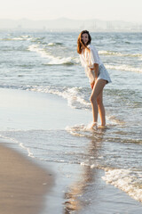 Fototapeta na wymiar Smiling woman in shirt looking at camera while standing in sea.