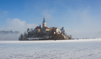 Winter morning at frozen lake Bled. Ice skating on the frozen lake. 