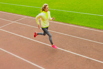 Obraz premium Outdoor training. A young woman runs around the stadium. Healthy lifestyle