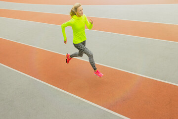 Obraz premium Top view of an athlete running on a treadmill. A young woman in a bright tracksuit. Competitions