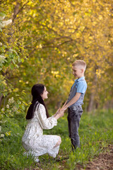 Fototapeta premium A mother with dark hair sits next to her son , looks at him and holds his hands