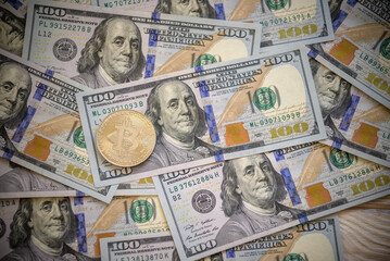 Golden symbolic coin Bitcoin on banknotes of one hundred dollars. Exchange bitcoin cash for a dollars. Cryptocurrency on US dollar bills. Digital modern method of payment. Savings, investments concept