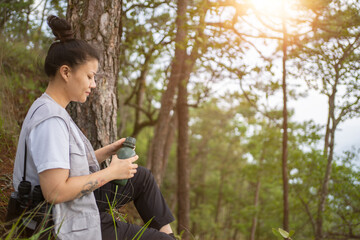 trekking concept ,Woman drinking water outdoors,Refreshment during hiking in forest,Female tourist resting