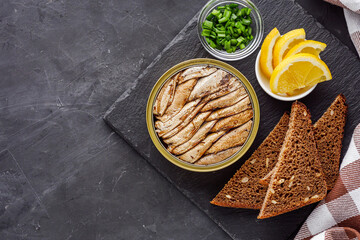 canned sprats in oil on a dark stone background