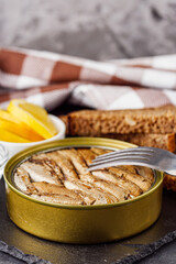 canned sprats in oil on a dark stone background