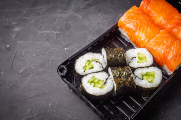 delicious sushi rolls in a delivery box on a black background