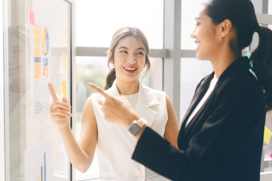 Happy Smile Two Young Adult Asian Woman Wearing Suit Talking About Strategy In Office