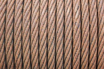 Steel cable sling hoist. Old obsolete rusty steel braided cable wounded on drum of industrial winch selective focuse macro closeup texture background.