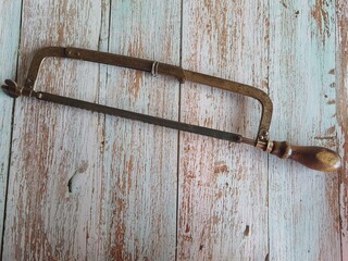 Old hand bow saw isolated on an old wooden table, top view.