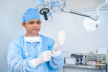 Surgeon waring gloves for performing surgery at operation theater - concept of preparation,...