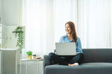 Asian business woman working with laptop on sofa.