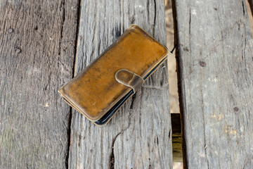 The smartphone is in a brown leather case on a wooden table