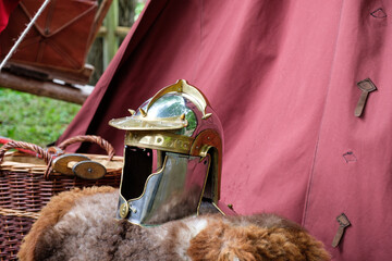 Römischer Helm / Legionärshelm auf einem Fell vor einem Zelt (Im Hintergrund ein Korb und ein Schwert)