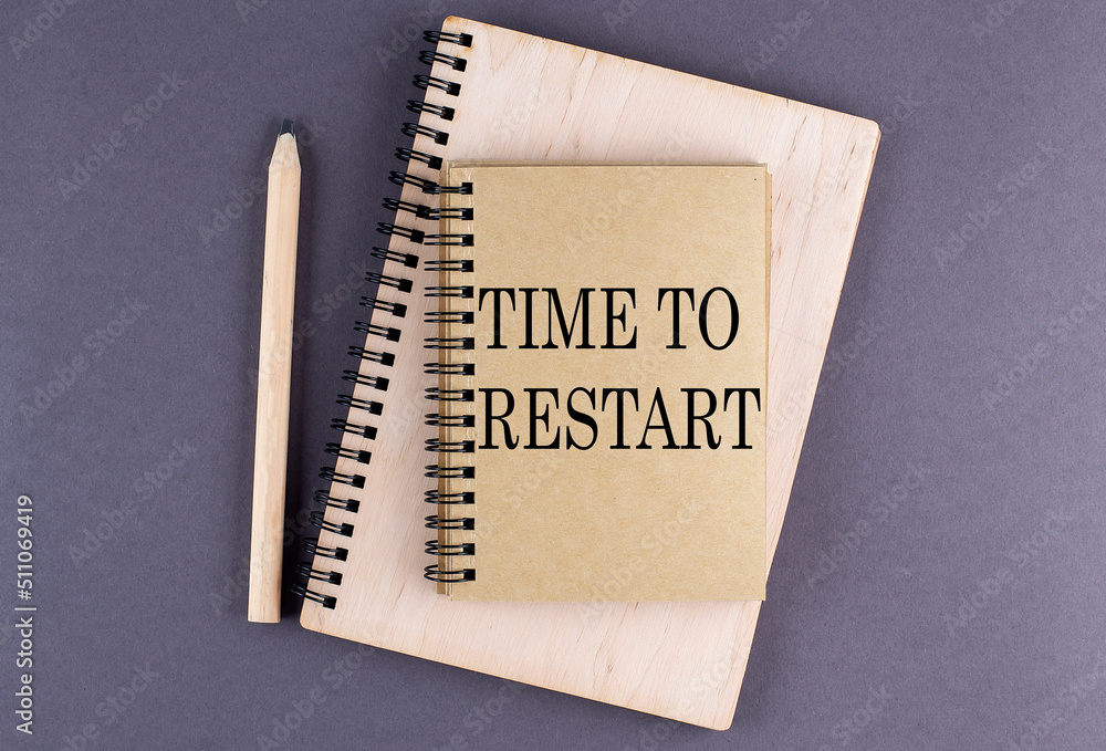 Aufkleber word time to restart on notebook with pencil on the grey background