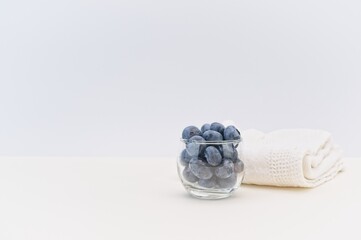 glass bowl with fresh organic blueberries and white kitchen towel on a white table