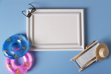 White frame with beach accessories, inflatable circles, sunglasses, and a chaise longue.