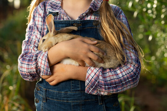 anonymous Little farmer with rabbit in garden