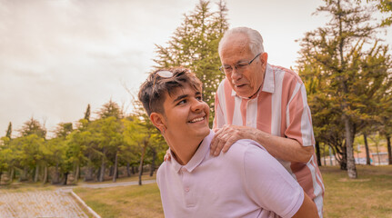 Nieto joven, cogiendo a su abuelo al hombro, con expresión sonriente, pasándoselo bien en el...