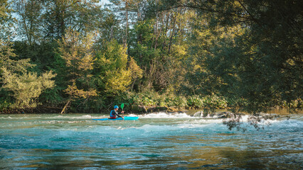 Fototapeta na wymiar Caucasian man kayaking upstream on the whitewater rapids, paddling hard on the turbulent river