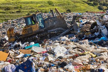 Heavy machinery shredding garbage in an open air landfill. Pollution