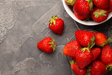 Fresh ripe strawberries in a plate on a black texture background.Vegetarian organic berry.Healthy food.Vitamins.Copy space.Place for text